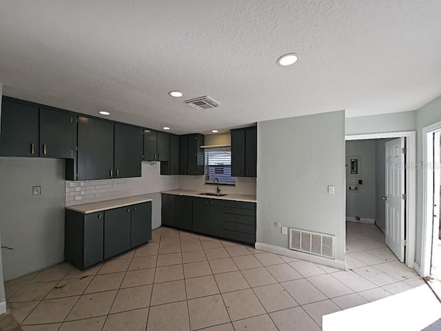 kitchen with visible vents, a sink, decorative backsplash, and light tile patterned flooring