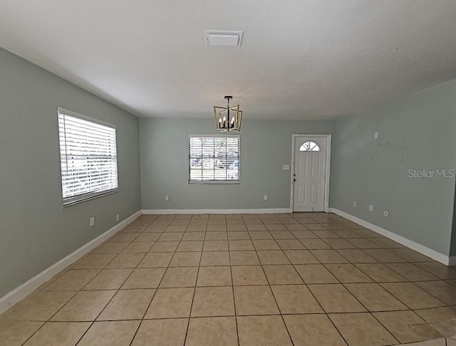 unfurnished room with visible vents, a notable chandelier, and baseboards