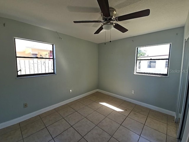 empty room with tile patterned flooring, baseboards, and a ceiling fan