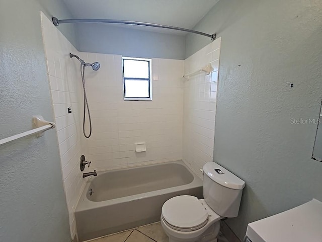 bathroom featuring toilet, tile patterned floors, shower / bathing tub combination, and a textured wall