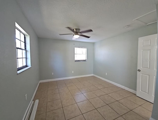 empty room with ceiling fan, a textured ceiling, baseboards, and light tile patterned floors