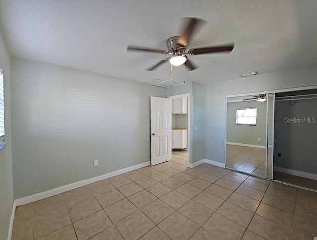 unfurnished bedroom featuring light tile patterned floors, a textured ceiling, attic access, and baseboards