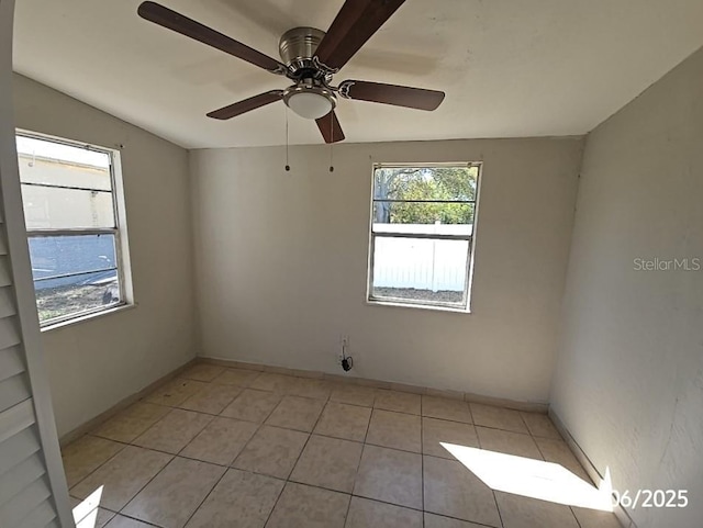 unfurnished room featuring a ceiling fan, light tile patterned flooring, and baseboards