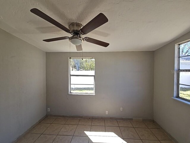 unfurnished room with ceiling fan, plenty of natural light, and light tile patterned floors