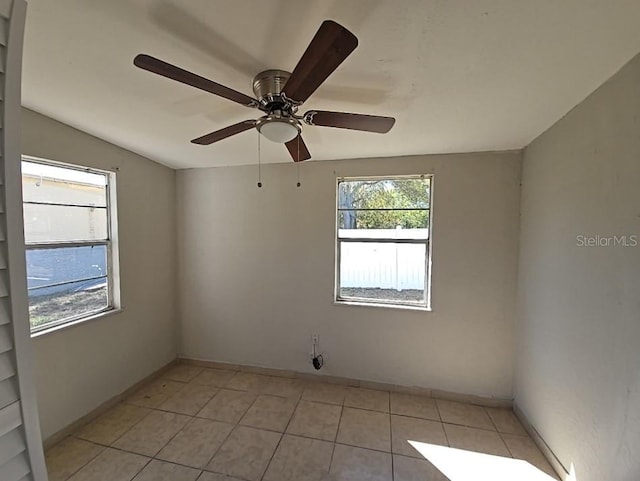 spare room featuring light tile patterned floors, baseboards, and a ceiling fan