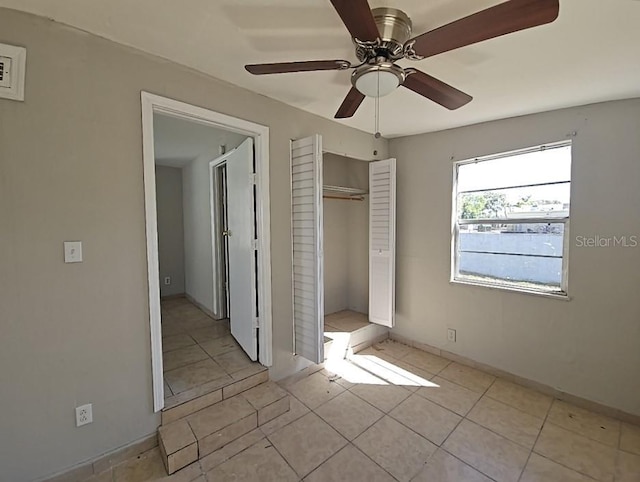 unfurnished bedroom featuring a closet, ceiling fan, baseboards, and light tile patterned floors