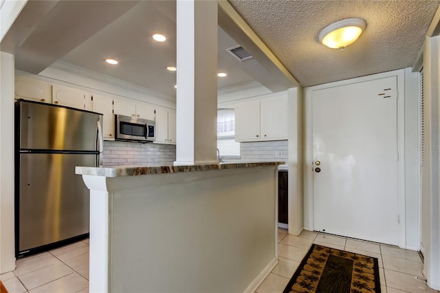 kitchen featuring stainless steel appliances, light tile patterned flooring, visible vents, and white cabinets