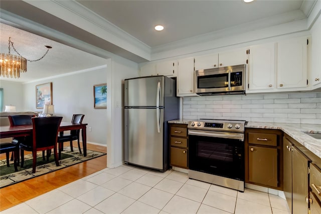 kitchen with white cabinets, appliances with stainless steel finishes, decorative backsplash, and ornamental molding