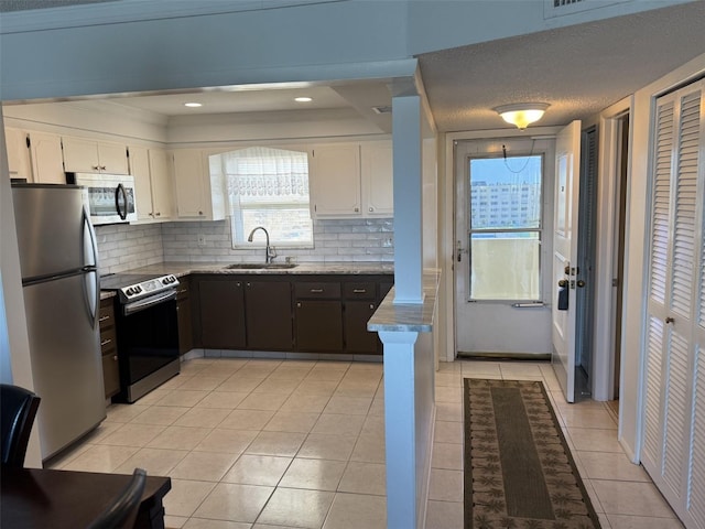 kitchen with white cabinetry, stainless steel appliances, a sink, and light tile patterned flooring