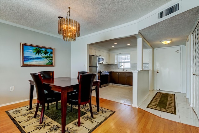 dining room with light wood finished floors, visible vents, and a textured ceiling