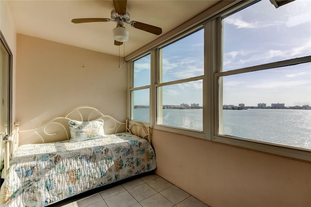 bedroom with light tile patterned flooring, a water view, and ceiling fan