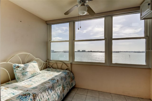 bedroom with light tile patterned floors, ceiling fan, and a water view