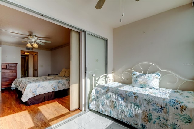 bedroom with ceiling fan, wood finished floors, visible vents, and crown molding