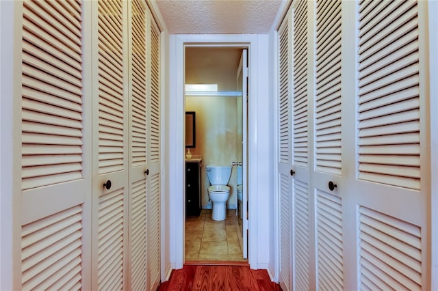 hallway with a textured ceiling and dark wood finished floors