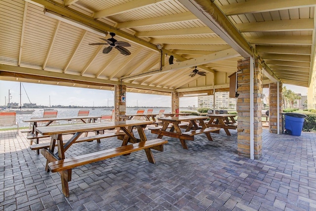 view of patio with a gazebo, outdoor dining area, a water view, and a ceiling fan