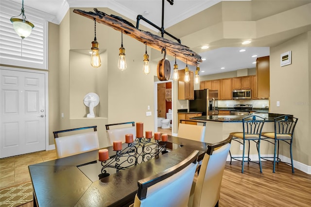 dining room with light wood finished floors, baseboards, ornamental molding, and recessed lighting