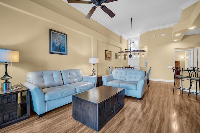 living area featuring ornamental molding, wood finished floors, a ceiling fan, and baseboards