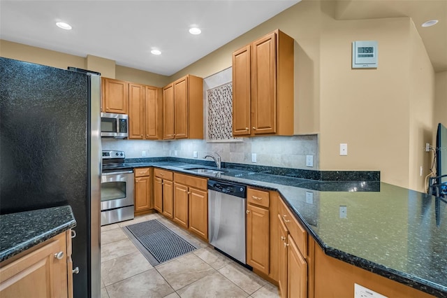 kitchen with tasteful backsplash, a peninsula, stainless steel appliances, a sink, and light tile patterned flooring