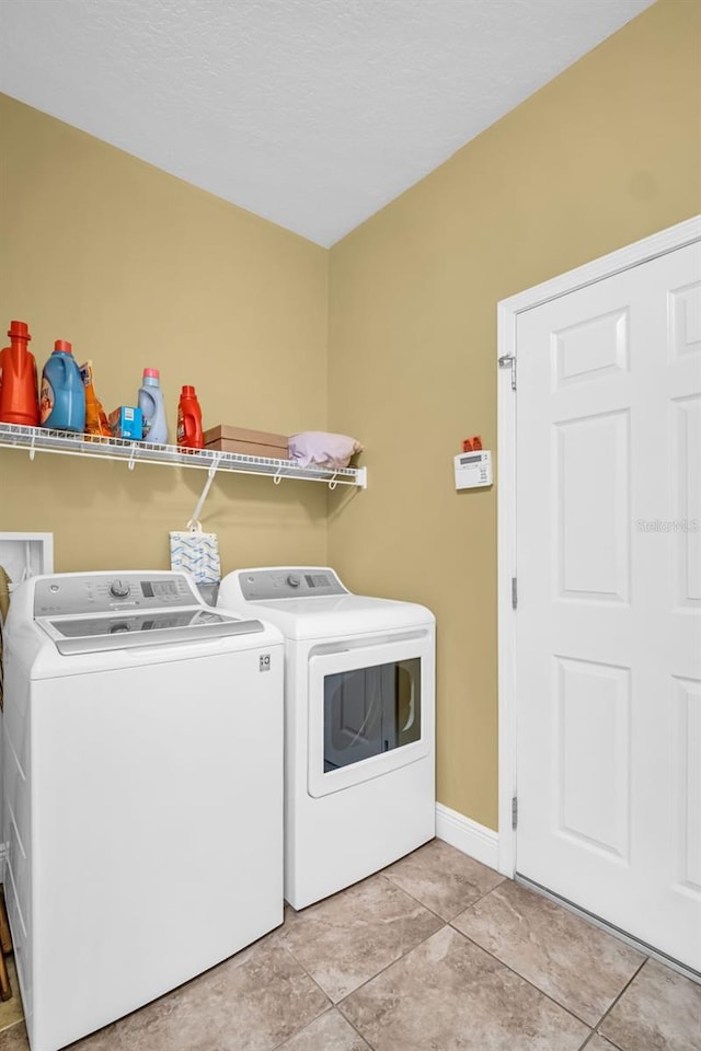 laundry room featuring laundry area, light tile patterned flooring, independent washer and dryer, and baseboards