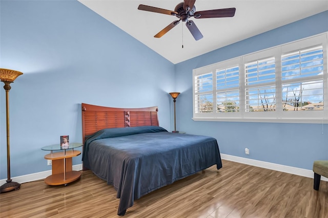 bedroom featuring a ceiling fan, vaulted ceiling, baseboards, and wood finished floors