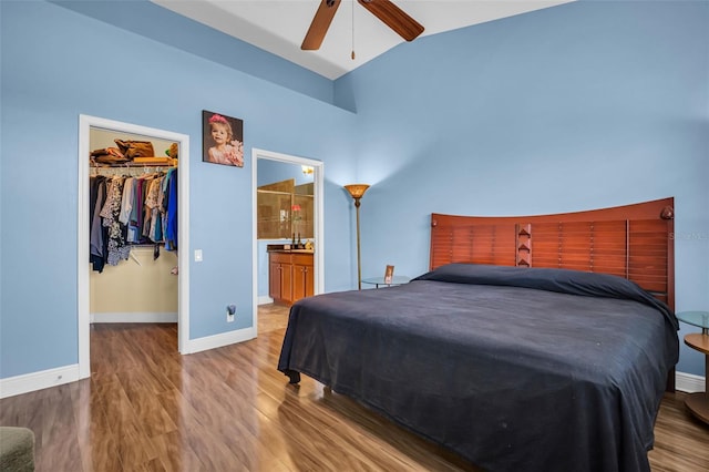 bedroom featuring wood finished floors, a ceiling fan, baseboards, a closet, and a walk in closet