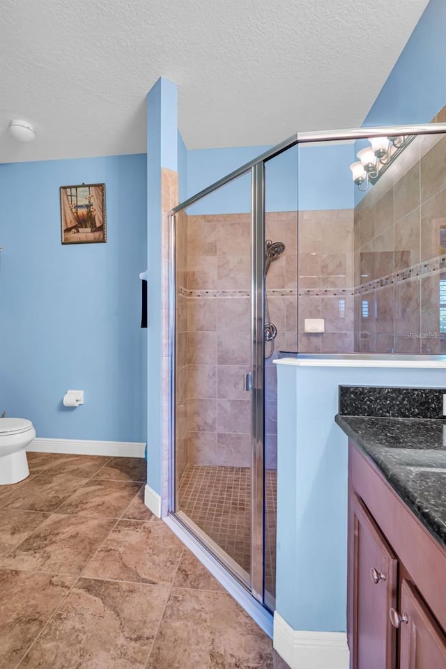 full bathroom featuring a stall shower, a textured ceiling, and vanity