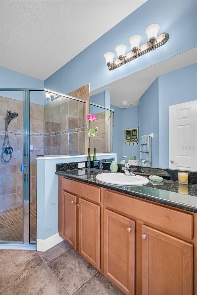 bathroom featuring a stall shower, tile patterned flooring, a textured ceiling, and vanity