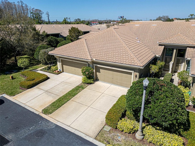 view of front of home featuring driveway, a tile roof, an attached garage, and stucco siding