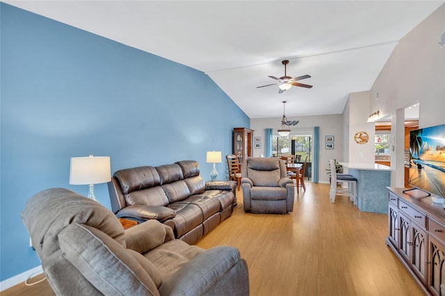 living area with vaulted ceiling, light wood-type flooring, a ceiling fan, and baseboards