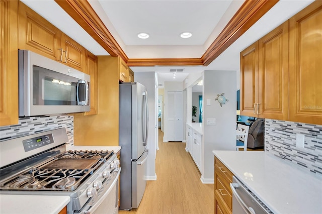 11430 94th St, Largo, FL 33773 - kitchen featuring light countertops, appliances with stainless steel finishes, brown cabinetry, light wood-style flooring, and visible vents