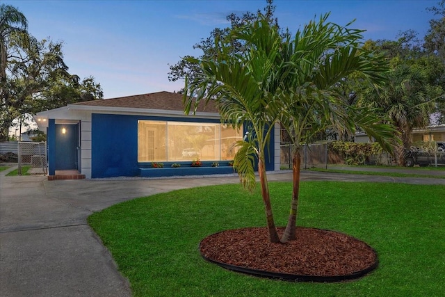 view of front of property featuring driveway, a front lawn, fence, and stucco siding