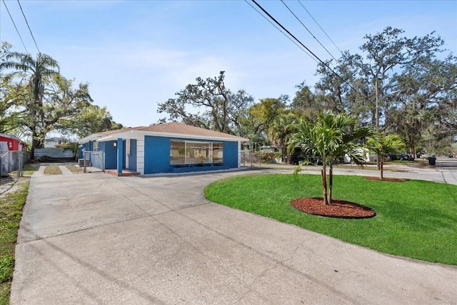 view of front facade featuring fence, a front lawn, and concrete driveway