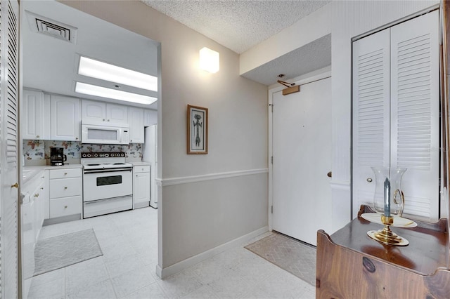 kitchen featuring a textured ceiling, white appliances, visible vents, white cabinetry, and light countertops