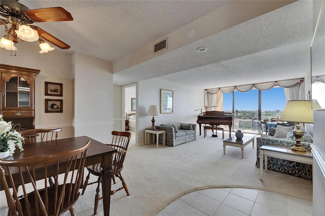 tiled dining space featuring a ceiling fan, a textured ceiling, visible vents, and carpet flooring