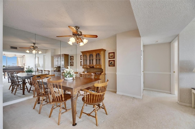 dining room featuring light colored carpet, visible vents, ceiling fan, a textured ceiling, and baseboards