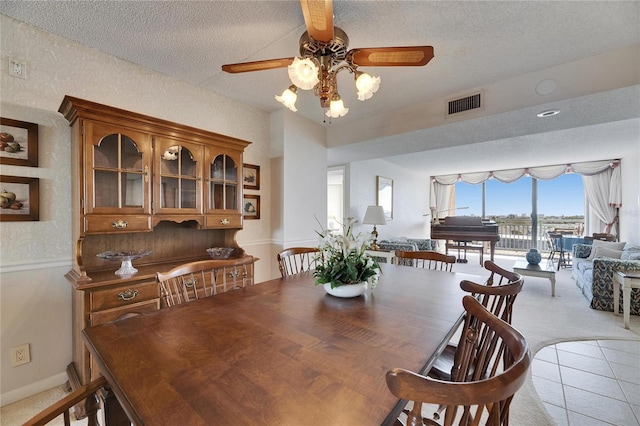 dining area with a textured ceiling, light tile patterned floors, light carpet, and visible vents