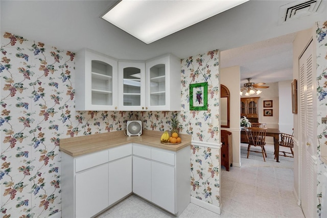 kitchen featuring glass insert cabinets, light countertops, visible vents, and wallpapered walls