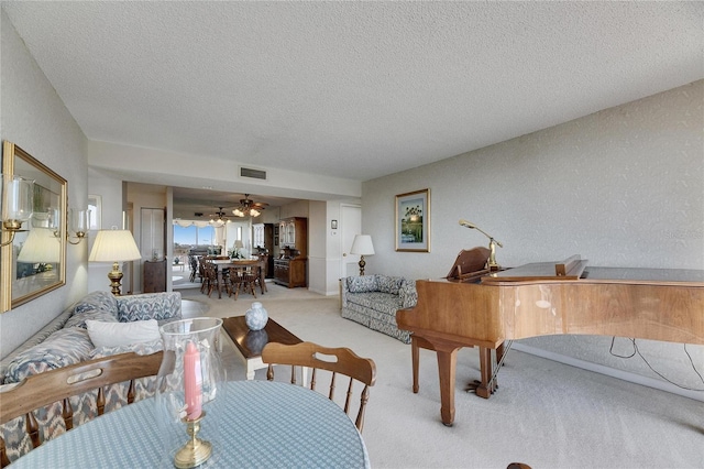 living room with light carpet, ceiling fan, visible vents, and a textured ceiling