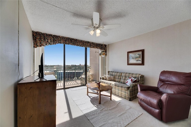 living area featuring carpet floors, a textured ceiling, and a ceiling fan