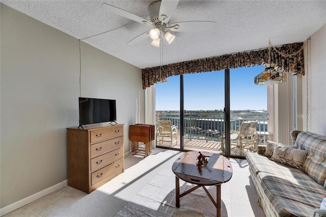 living room featuring a ceiling fan, light carpet, a textured ceiling, and baseboards