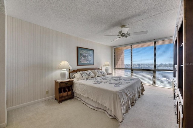 bedroom with light carpet, baseboards, a ceiling fan, a textured ceiling, and floor to ceiling windows