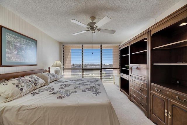 carpeted bedroom featuring a textured ceiling, ceiling fan, and wallpapered walls