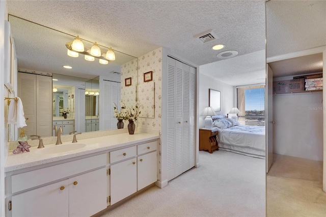 ensuite bathroom with a closet, visible vents, a textured ceiling, and wallpapered walls