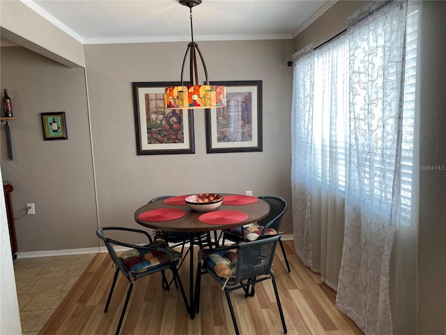 dining area featuring baseboards, light wood-style flooring, and crown molding