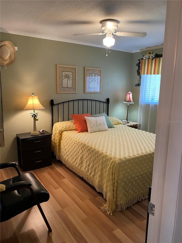 bedroom with a textured ceiling, ornamental molding, wood finished floors, and a ceiling fan