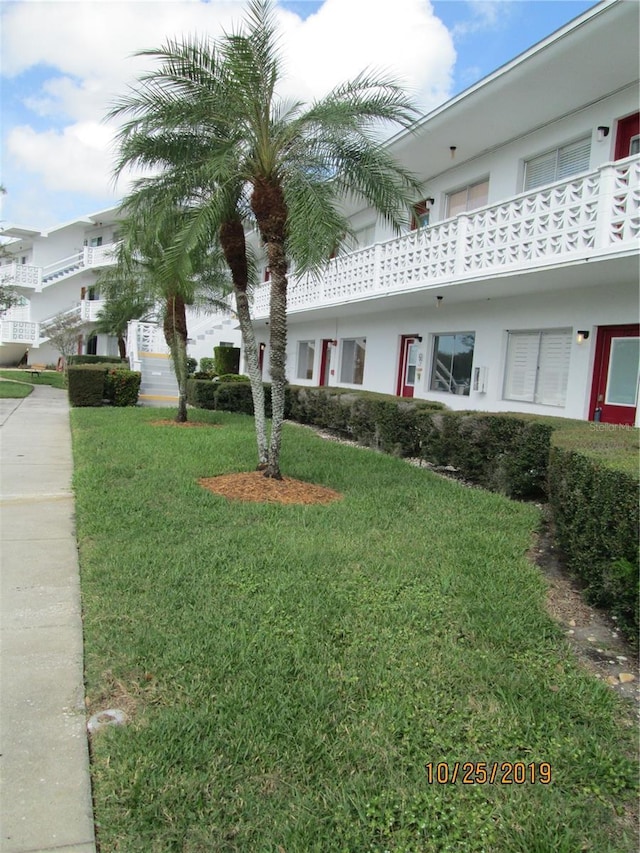 exterior space with a front yard, a balcony, and stucco siding