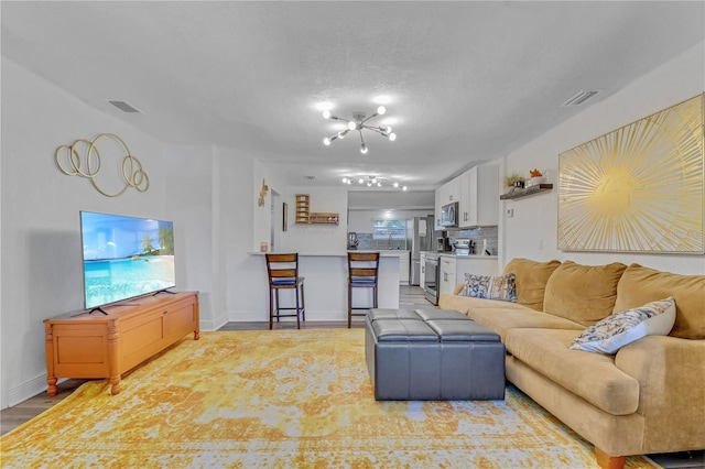 living room featuring light wood-style floors, visible vents, and baseboards