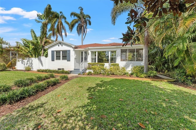 view of front of home with a front lawn, fence, and stucco siding