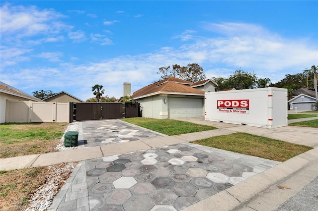 exterior space featuring driveway, an attached garage, a gate, and fence