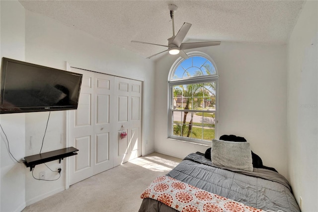 carpeted bedroom featuring ceiling fan, a closet, vaulted ceiling, and a textured ceiling